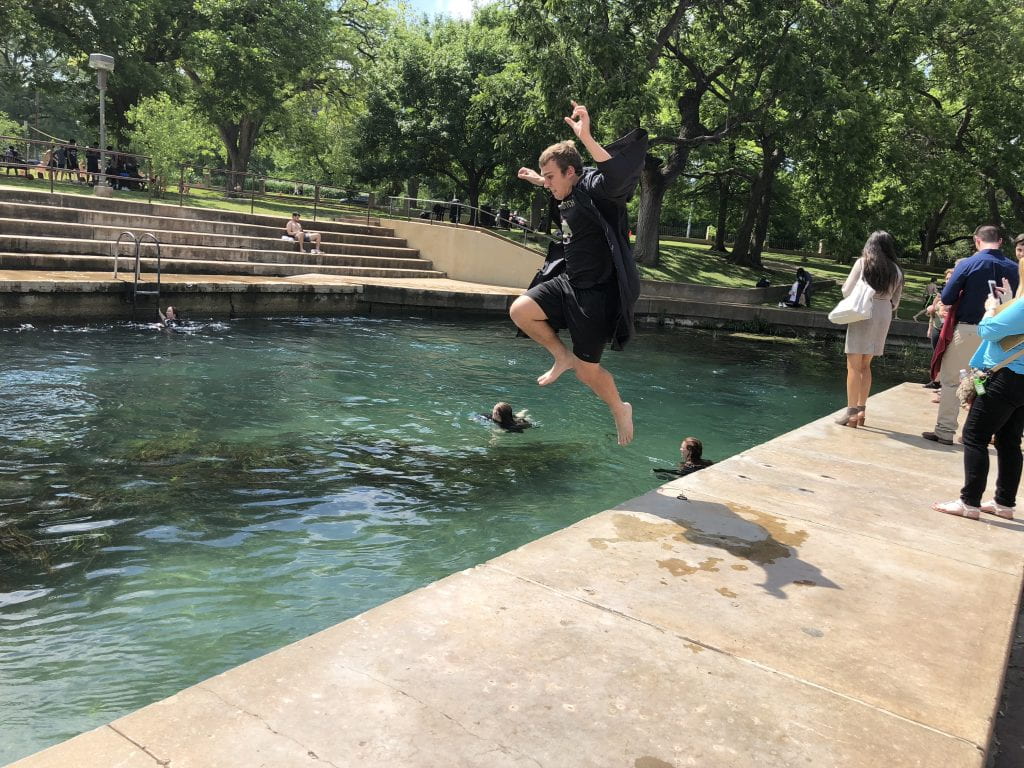 B.S. Chemist Steven Gralinski celebrates with the Texas State tradition of jumping into the San Marcos River after graduation