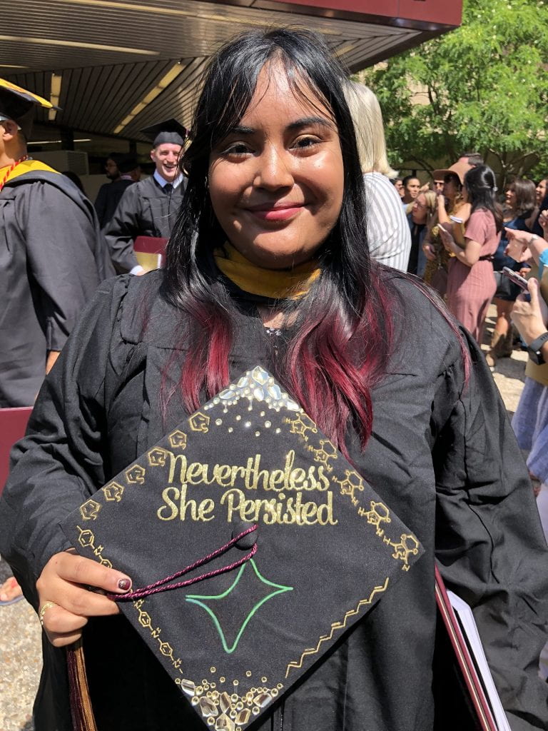 photo of a girl in graduation regalia holding her cap decorated with "Nevertheless She Persisted," a cyclic voltammorgra, and polymer structures