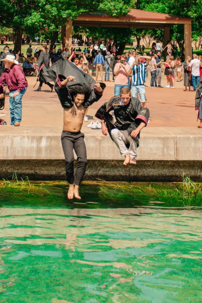 Two men jumping into a river in regalia